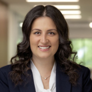 Brianne, a white woman with brown hair, wears a white blouse and black suit.