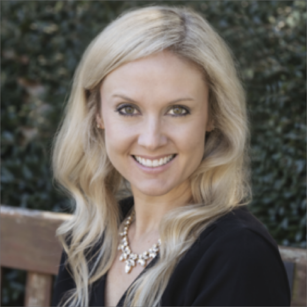 Kate, a white woman with wavy blond hair, wears a black dress and silver necklace. She is smiling.