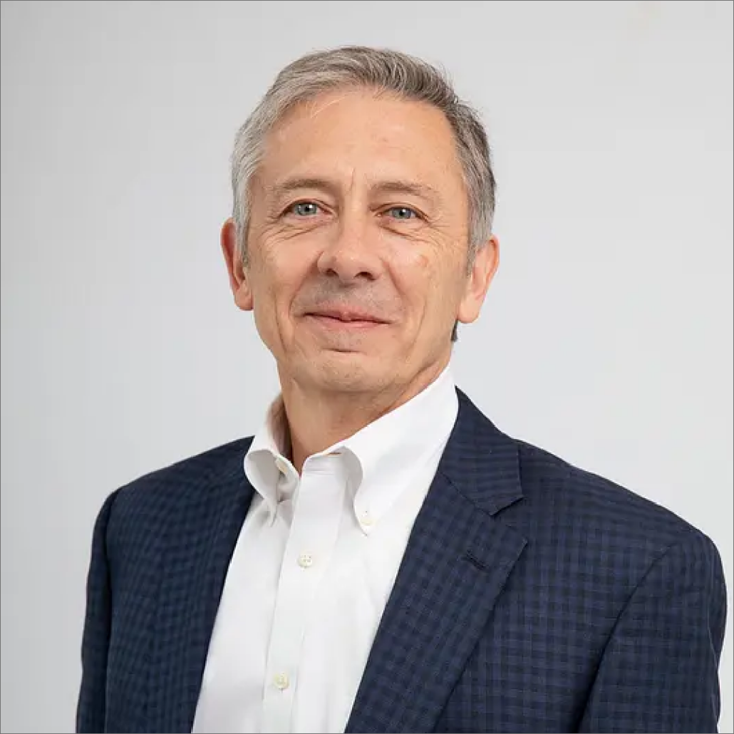 Mike, a white man with grey hair, wears a white shirt and navy suit.