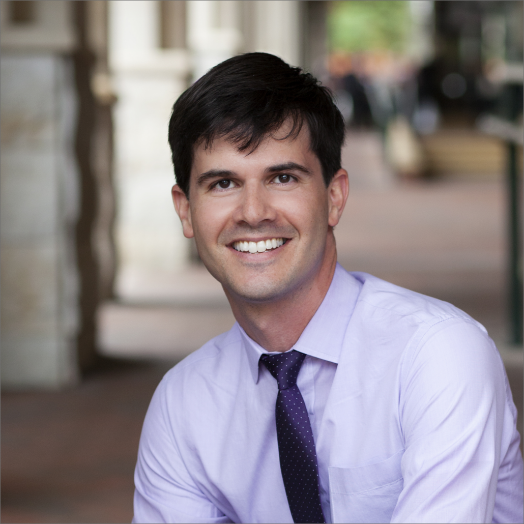 David, a white man with dark brown hair, wears a pale purple shirt a dark grey tie.