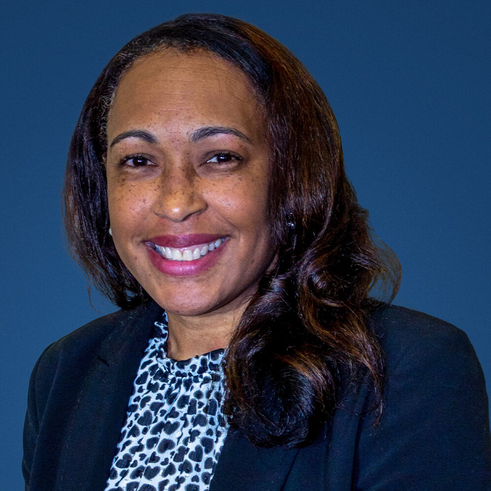 Scheree, a woman with dark brown hair, wears a blue and white shirt and navy blazer.