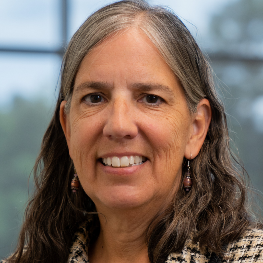 Terri, a woman with brown hair, wears a black, white and gold blouse and is pictured smiling.