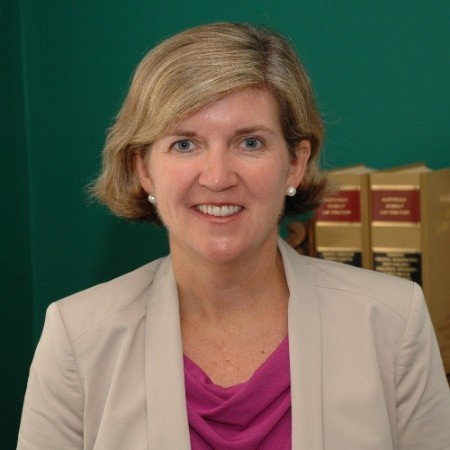 Elizabeth, a woman with short blond hair, wears a pink blouse and khaki blazer.