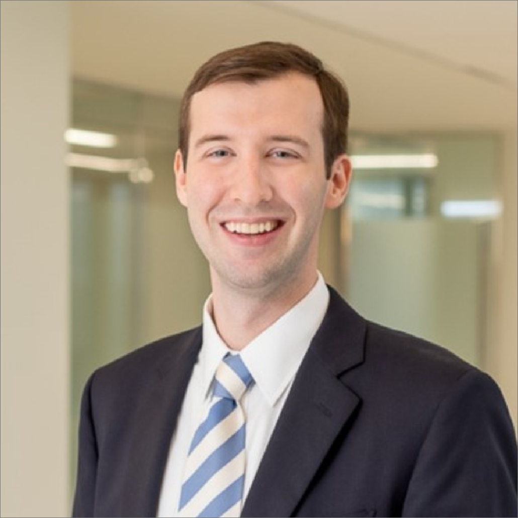 Will, a white man with brown hair, wears a white shirt, blue and yellow striped tie, and black suit.