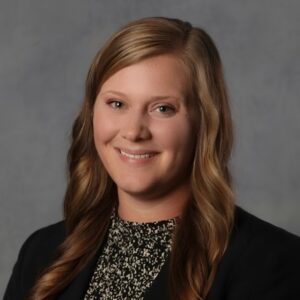 Lauren, a white woman with light brown hair, wears a black and white top and black blazer.