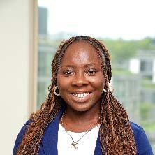 Keshia, a Black woman with long brown hair, wears a white blouse with a blue blazer.