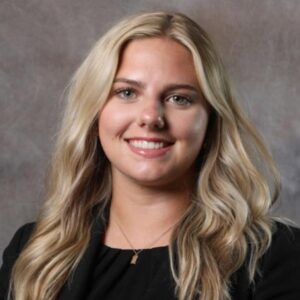 Sarah, a white woman with blond hair, wears a black blouse.