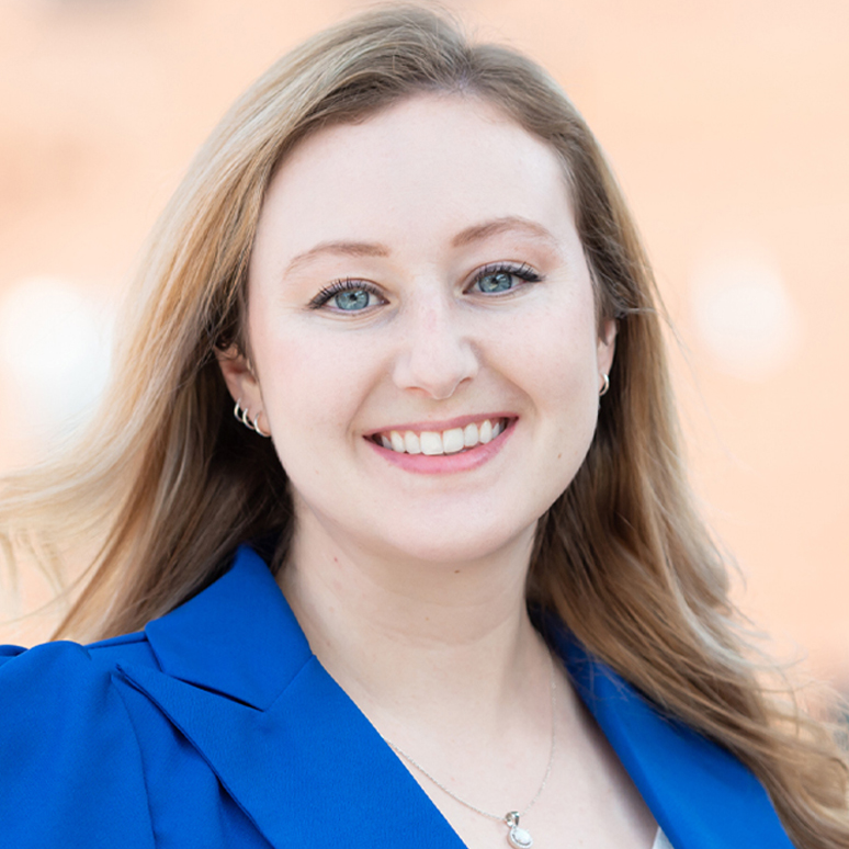 Tiffany, a white woman with medium blond hair, wears a white shirt and blue blazer.