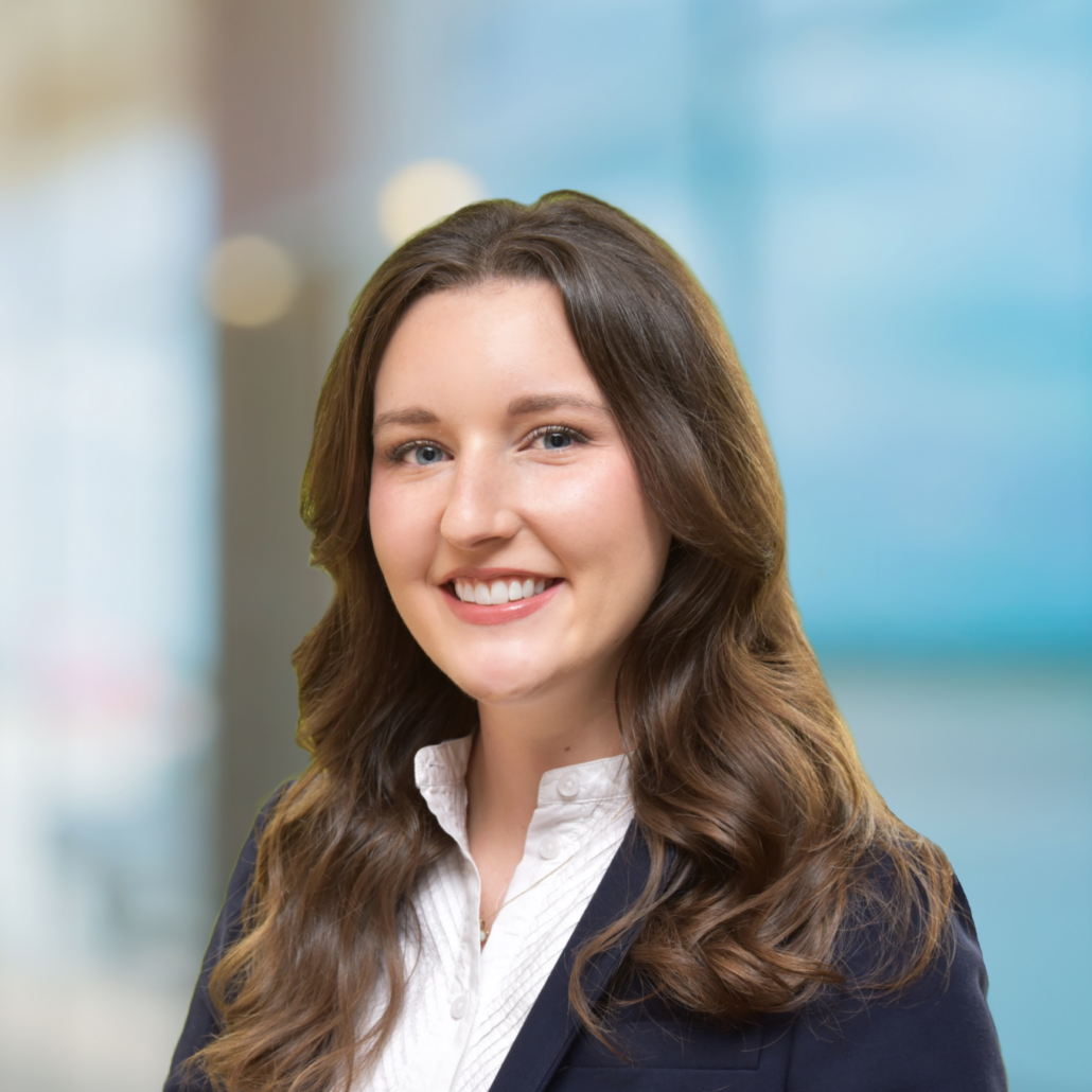 Andrea, a white woman with wavy brown hair, wears a white shirt and black suit.