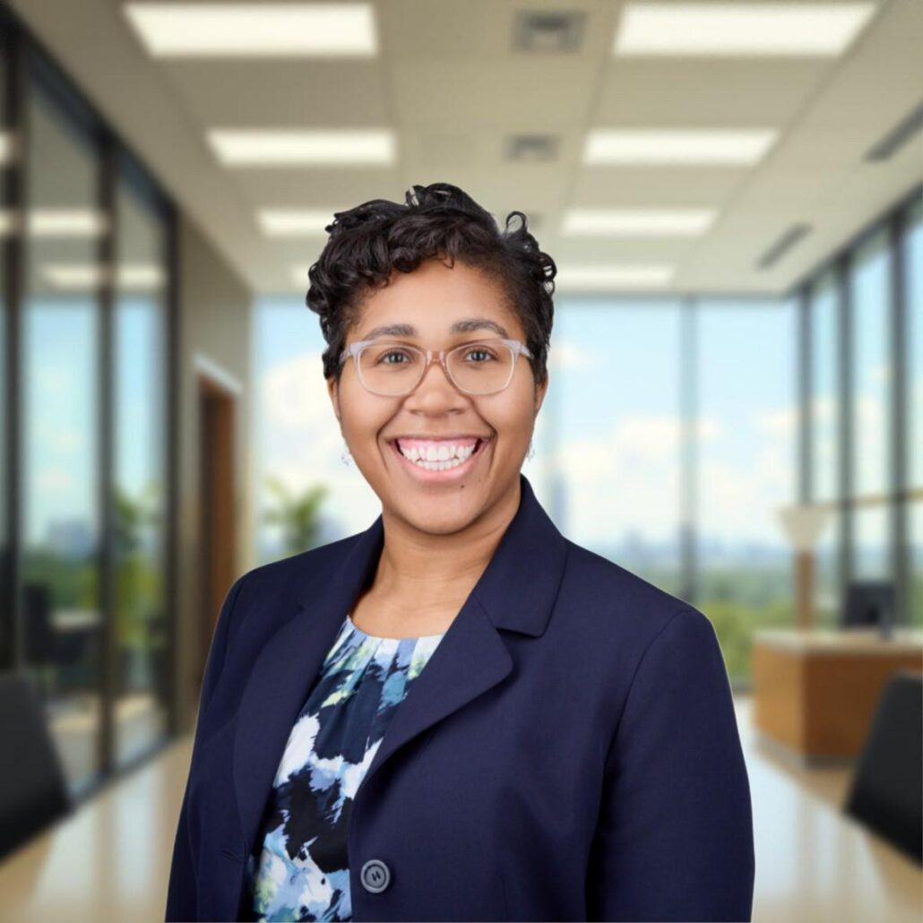 Taylor, a Black woman with dark brown hair, wears a blue and white blouse and navy blue blazer.
